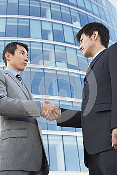 Businessmen Shaking Hands Against Office Building