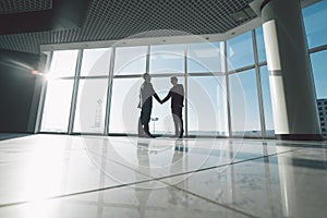 Businessmen shaking hands in against panoramic windows