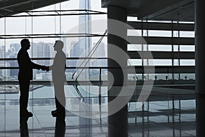 Businessmen Shaking Hands In Airport Terminal