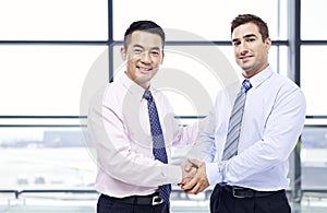 Businessmen shaking hands at airport