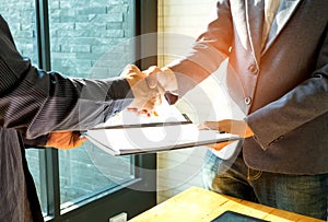 Businessmen are shaking hands and exchanging business documents.