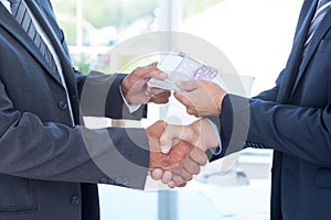 Businessmen shaking hands and exchanging money