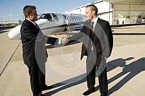 Businessmen shaking hands in front of corporate je