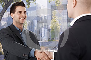 Businessmen shaking hands in front of office