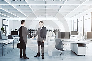 Businessmen shaking hands in modern concrete coworking office interior with furniture, equipment and window with city view,