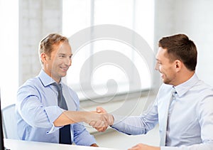 Businessmen shaking hands in office