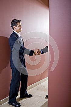 Businessmen shaking hands in office corridor