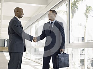 Businessmen Shaking Hands In Office Corridor