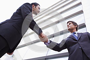 Businessmen shaking hands outside office building