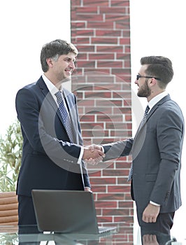 Businessmen shaking hands while standing in office corridor