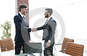 Businessmen shaking hands while standing in office corridor