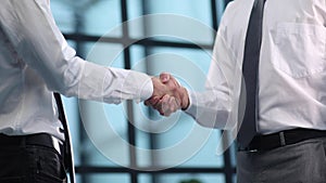 businessmen shaking hands while standing in the office corridor close-up