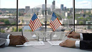 Businessmen signing papers at table.