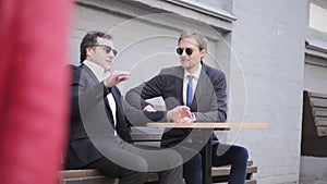 Businessmen sit drinking coffee in the street after lunch