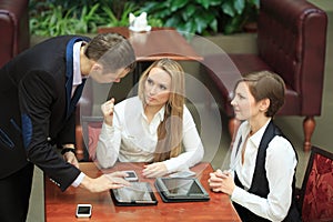 Businessmen sitting in cafe for a laptop. two girls