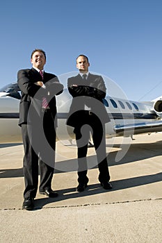 Businessmen standing in front of corporate jet