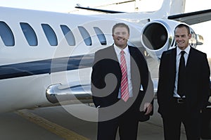 Businessmen standing in front of corporate jet