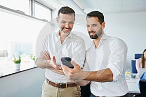 businessmen standing in office discussing looking on the phone