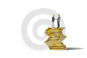 Businessmen standing on stacked golden coins and shaking hand together isolated on white background.