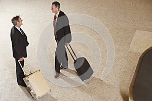 Businessmen With Suitcases By Luggage Carousel In Airport