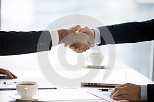Businessmen in suits handshake after successful negotiation closing deal, closeup photo
