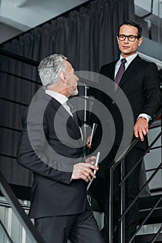 businessmen in suits having conversation while going down on steps