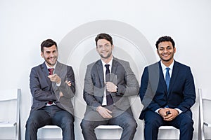 Businessmen in suits sitting on chairs at white waiting room