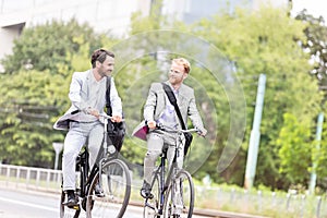 Businessmen talking while cycling outdoors