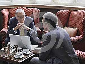 Businessmen Talking Over Laptop In Lobby
