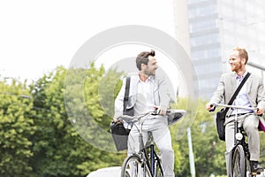 Businessmen talking while riding bicycles outdoors