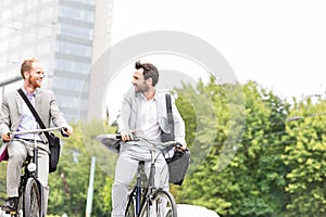 Businessmen talking while riding bicycles outdoors