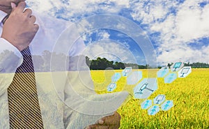 Businessmen use tablet to participate in auction, with icon of agricultural product auctioneer, sky background and organic fields,