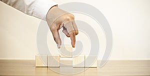 Businessmen use their hands to hold the rectangular wooden blocks arranged in a row