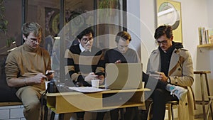 Businessmen using smartphones in cafe. Freelancers having break during meeting