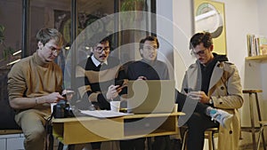 Businessmen using smartphones in cafe. Relaxed friends hanging at coffeehouse