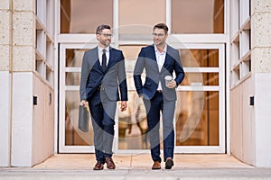 Businessmen walk in the street. Two businessmen walking and talking at office building. Two american businessmen in