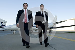 Businessmen walking away from corporate jet