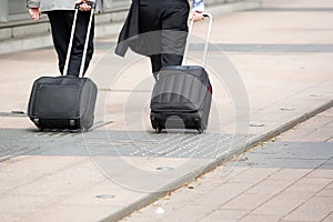 Businessmen walking with wheeled luggage