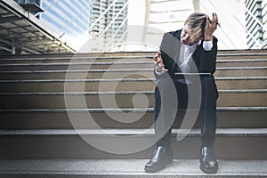 Businessmen Wear a black suit Sitting on a concrete stair He is having headaches and stress from unsuccessful plans