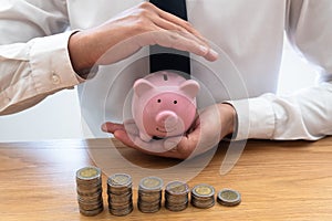 Businessmen who hold a piggy bank and place a coin as a graph showing savings, expanding a growing business for success and saving