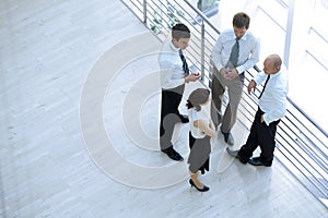 Businessmen and woman standing together by railing and conversing photo