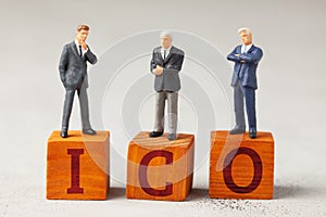 Businessmen and the word ICO and investments on a gray background.