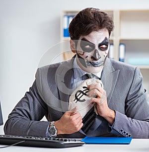 Businessmsn with scary face mask working in office