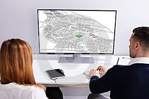 Businesspeople Analyzing Cadastre Map On Computer photo