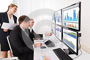 Businesspeople Analyzing Graphs On Multiple Computers