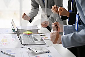 Businesspeople clenching their fists in the meeting to cheer up and show spirit of teamwork