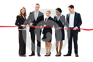 Businesspeople Cutting Red Ribbon With Scissors