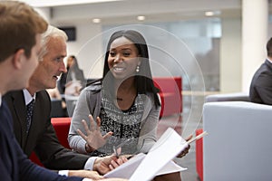 Businesspeople Discuss Document In Lobby Of Modern Office