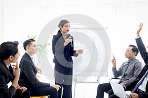 Businesspeople discussing at conference, businesswoman speaker holding microphone while lecturing presentation at group board.