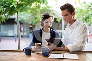 Businesspeople discussing over digital tablet at counter